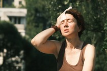 A woman dabs her sweaty forehead.