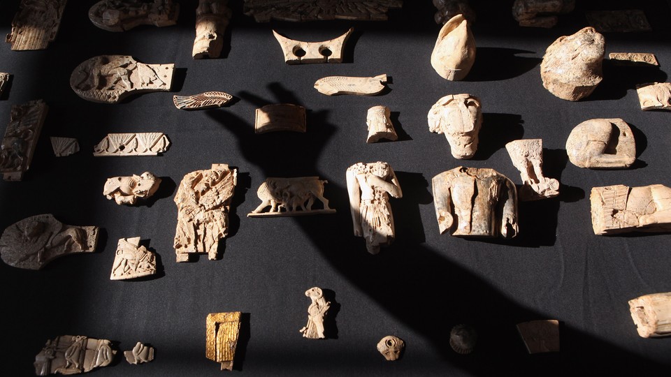 A technician at the British Museum casts a shadow over carved ivory artifacts from Nimrud, Iraq.