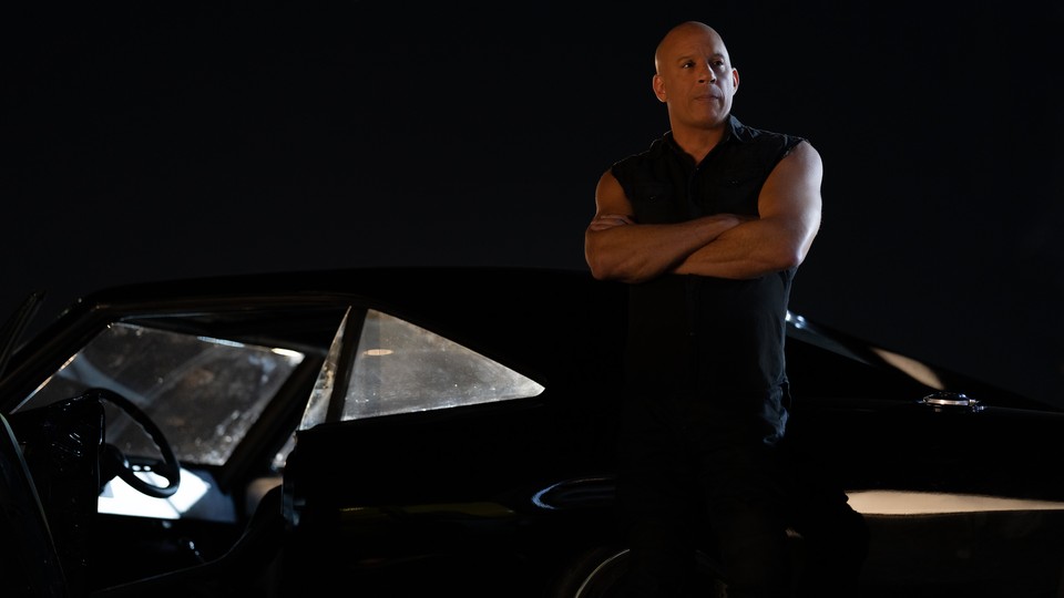 Vin Diesel stands with his arms crossed while leaning against a car, at night, in "Fast X"