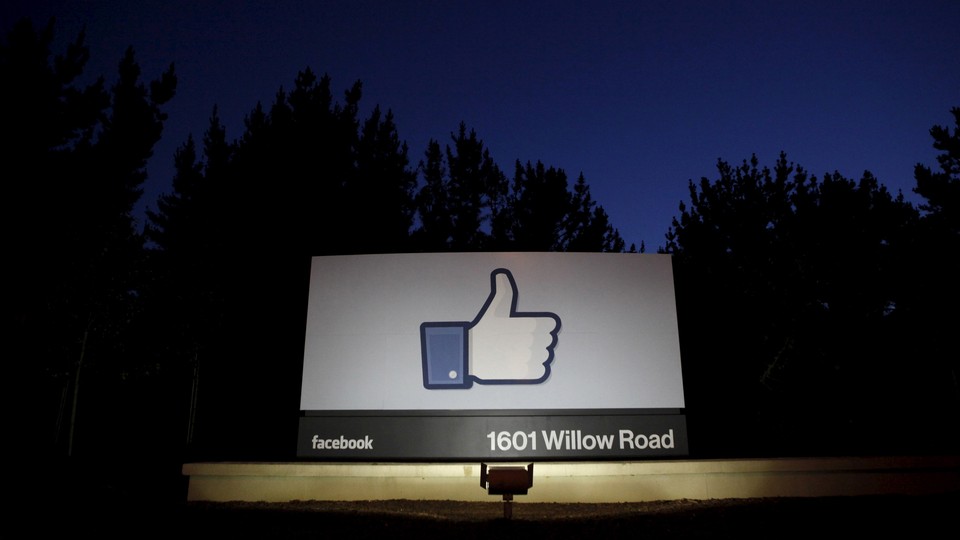 A Facebook "like" symbol illuminated at night on a sign that says "1601 Willow Road"