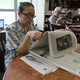 A woman reads a newspaper in a library.