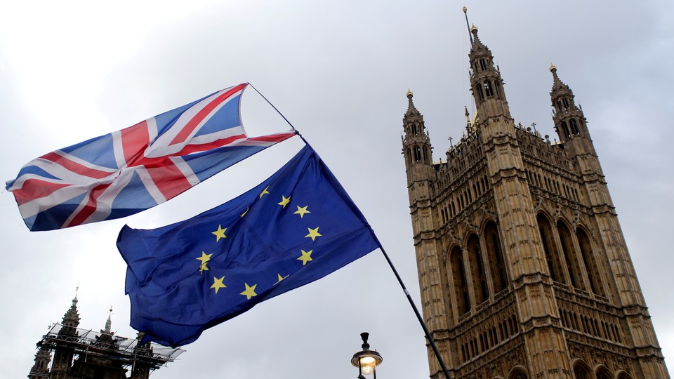 A British flag flies atop an EU flag outside the British Parliament.