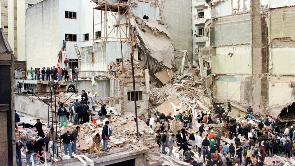 Old photograph of people standing in the wreckage of a bombed building.