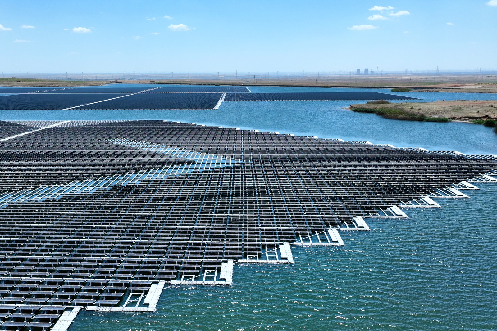 Floating solar panels sit in several grids on the surface of a reservoir.