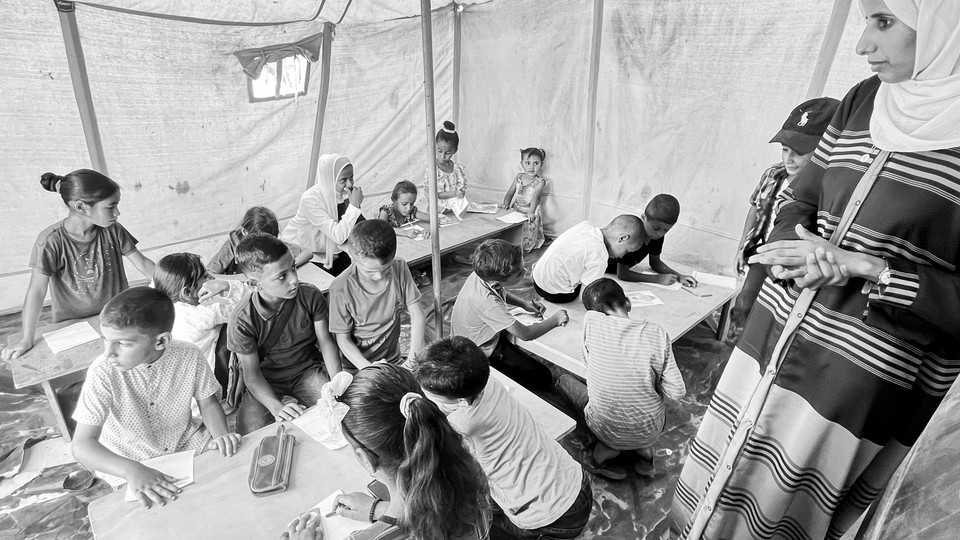 a black and white photograph of kids studying in a tent in Gaza.