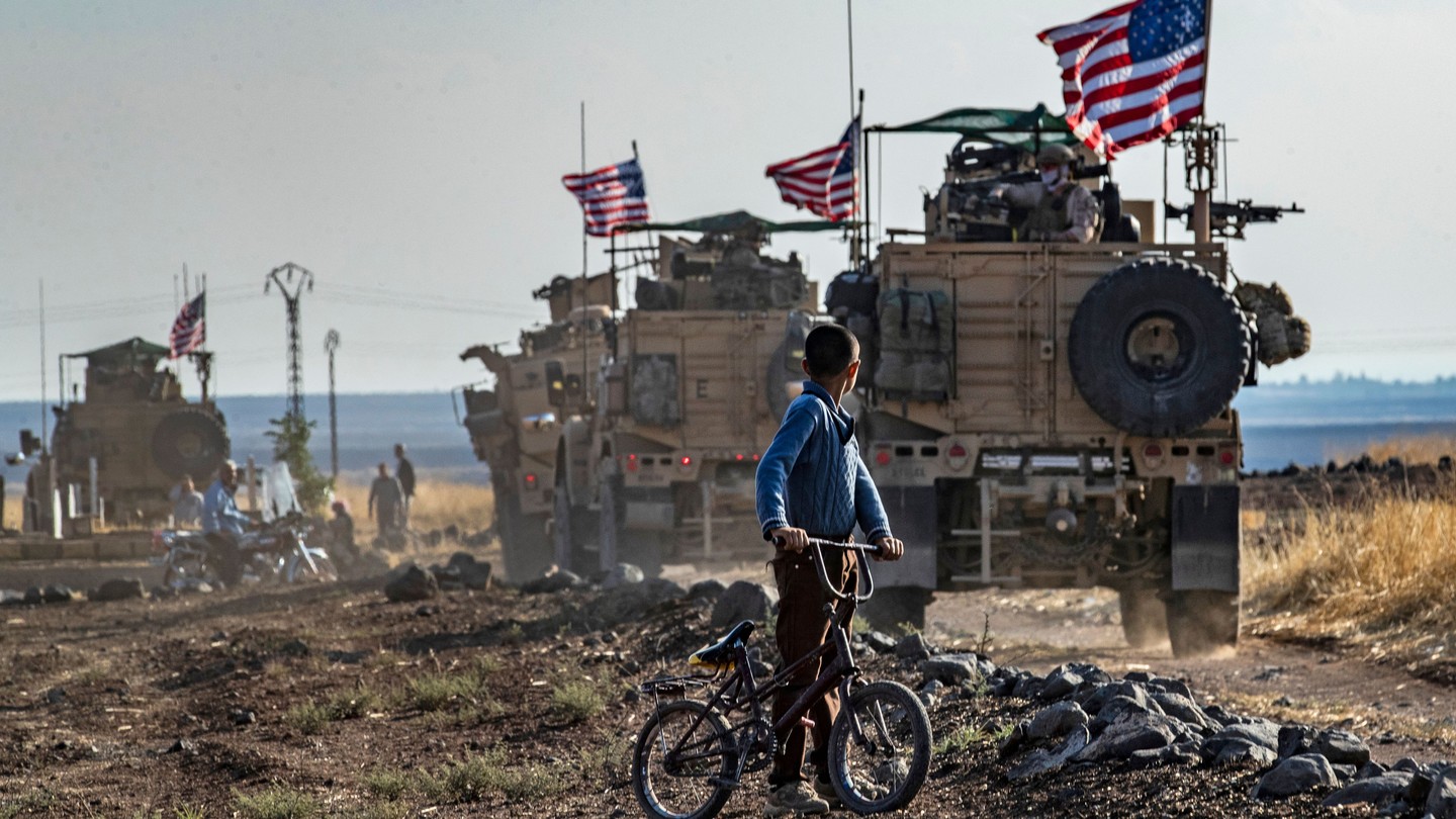 A Syrian boy on a bicycle watched a convoy of US armored vehicles drive away on a dirt road in northeastern Syria.