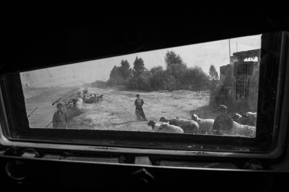 a boy and sheep seen through the window of a military vehicle