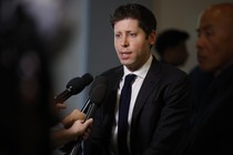 Sam Altman in a suit in front of microphones