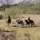 people ride in a covered wagon with mountains in the background