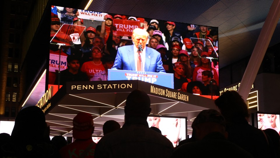 Rallygoers watch Donald Trump.
