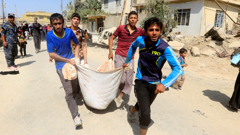 Displaced Iraqi men carry a wounded boy from clashes in western Mosul, Iraq on June 3, 2017. 