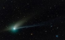 A comet against a backdrop of stars. The comet looks like a bright, greenish smudge with two different "tails."