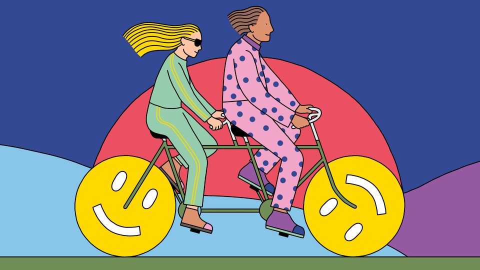 Two people ride a tandem bicycle, the wheels of which are smiley faces.