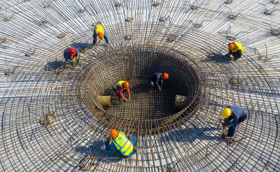 Construction workers attend to a circular section of a construction project.
