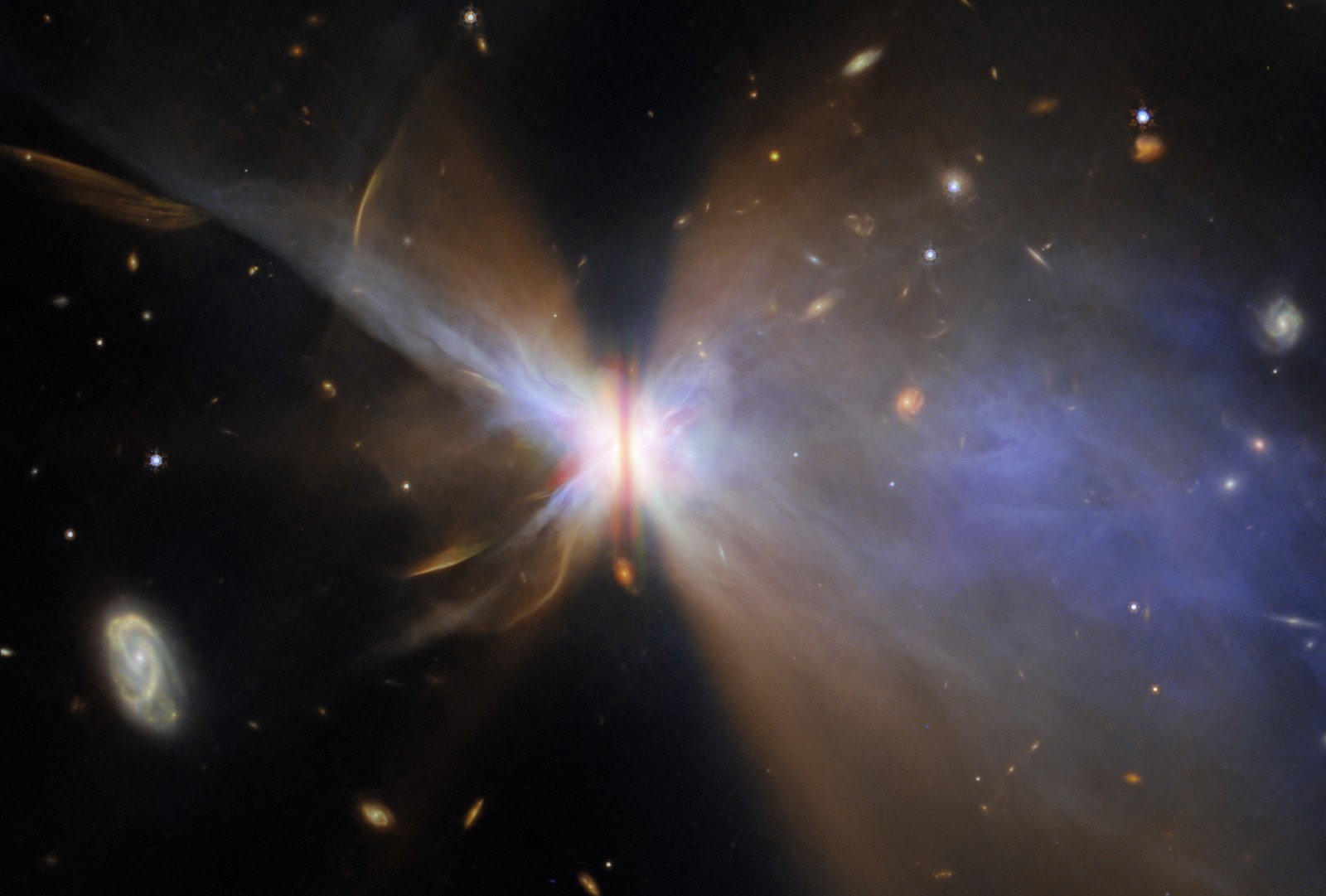 Distant galaxies appear in the background of this image from deep space, with a dark disc of dust seen edge-on at center, surrounded by clouds of dust and gas.