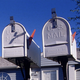A color photograph of two gray metal mailboxes with their signaling flags up