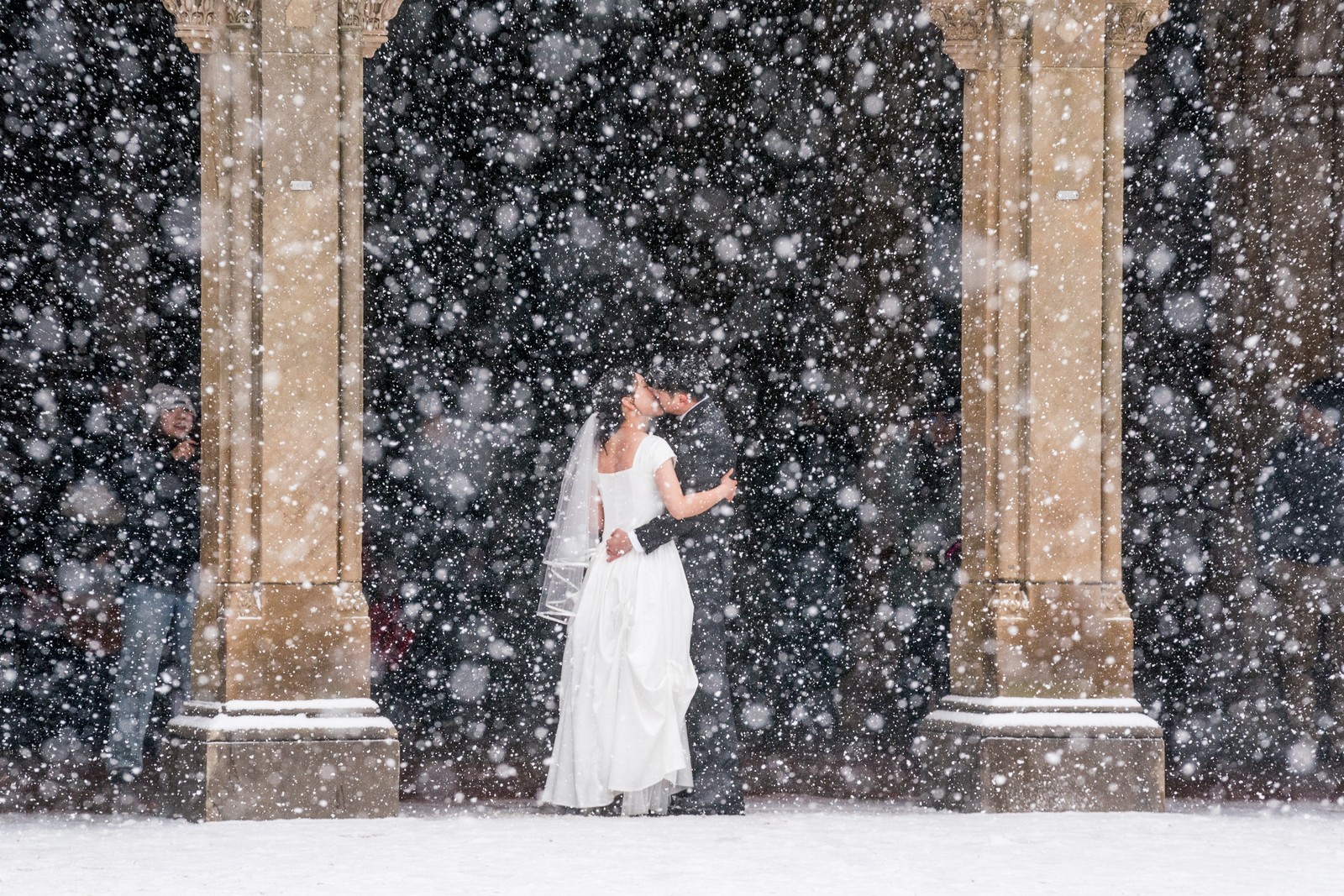A couple poses for wedding photos in Central Park during a snowstorm.
