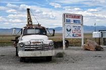 A tow truck parked beside a sign for the Little A'Le'Inn in Rachel, Nevada