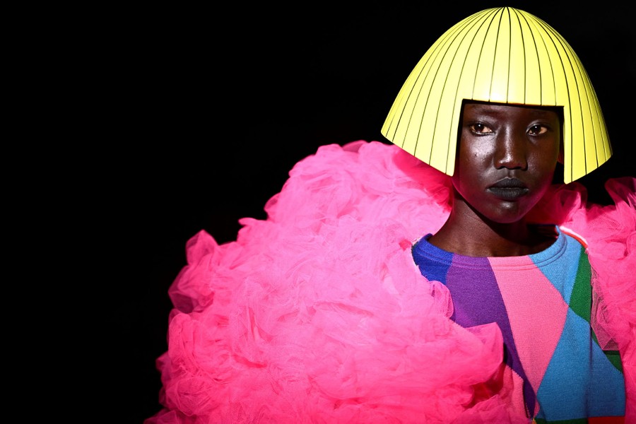 A model displays a colorful garment and a head covering made to resemble a slick yellow bob.