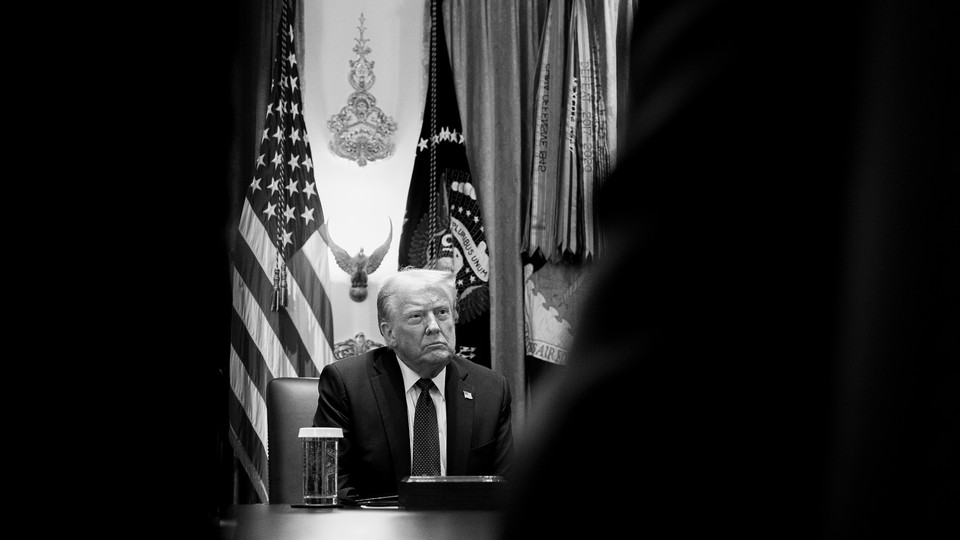 Black-and-white photo of President Trump in front of flags.