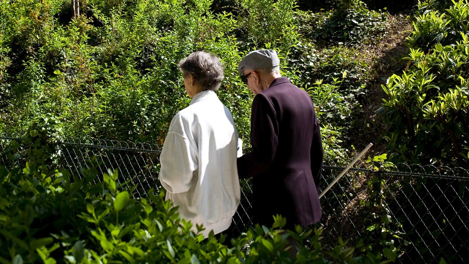Photo of two people walking arm-in-arm in a park