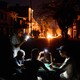 People illuminate themselves with their phones while playing dominoes, while, in the background, a fire set up by residents protesting against prolonged power outages burns on a street in Havana, at night.