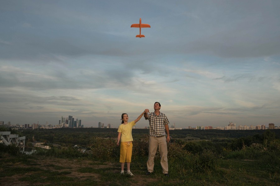 A father launches a small toy plane with his daughter.