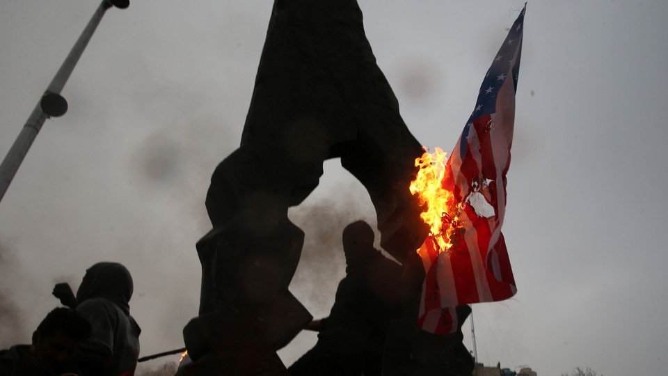 Iranians burn U.S. and Israeli flags.