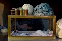 an empty case on a table with tortillas next to it and plastic containers with sauces on top