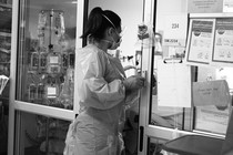 A health-care worker stands in the doorway of a patient's room.