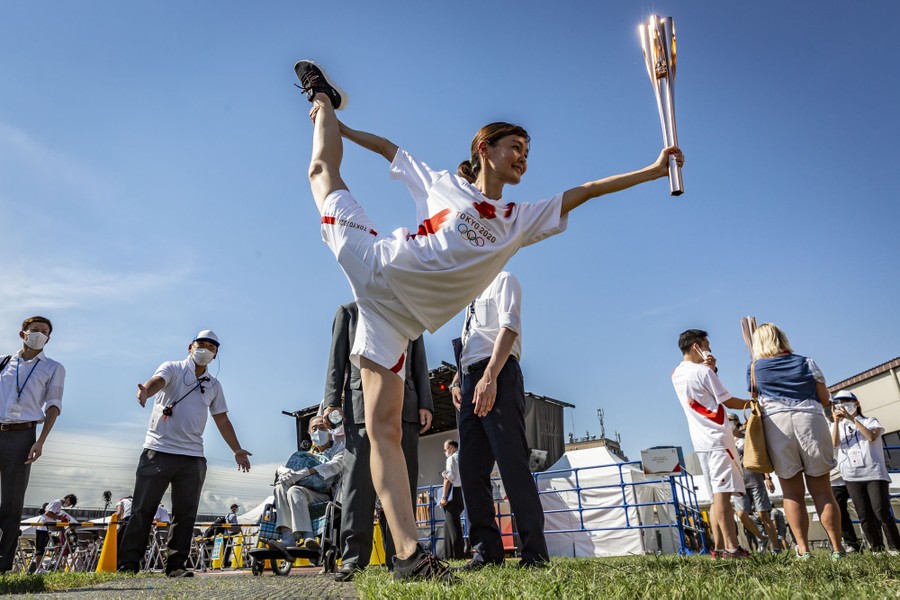 A torchbearer poses, standing on one foot.