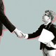 A child in a suit shakes hands with an adult businessman.