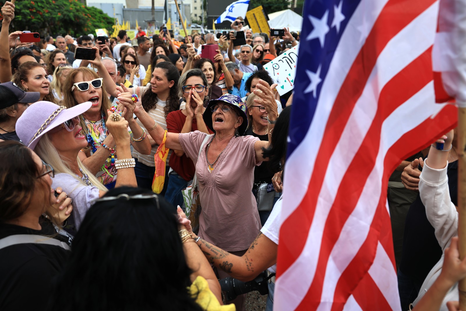 A crowd of people celebrate in a city square Israel, holding up an American flag.