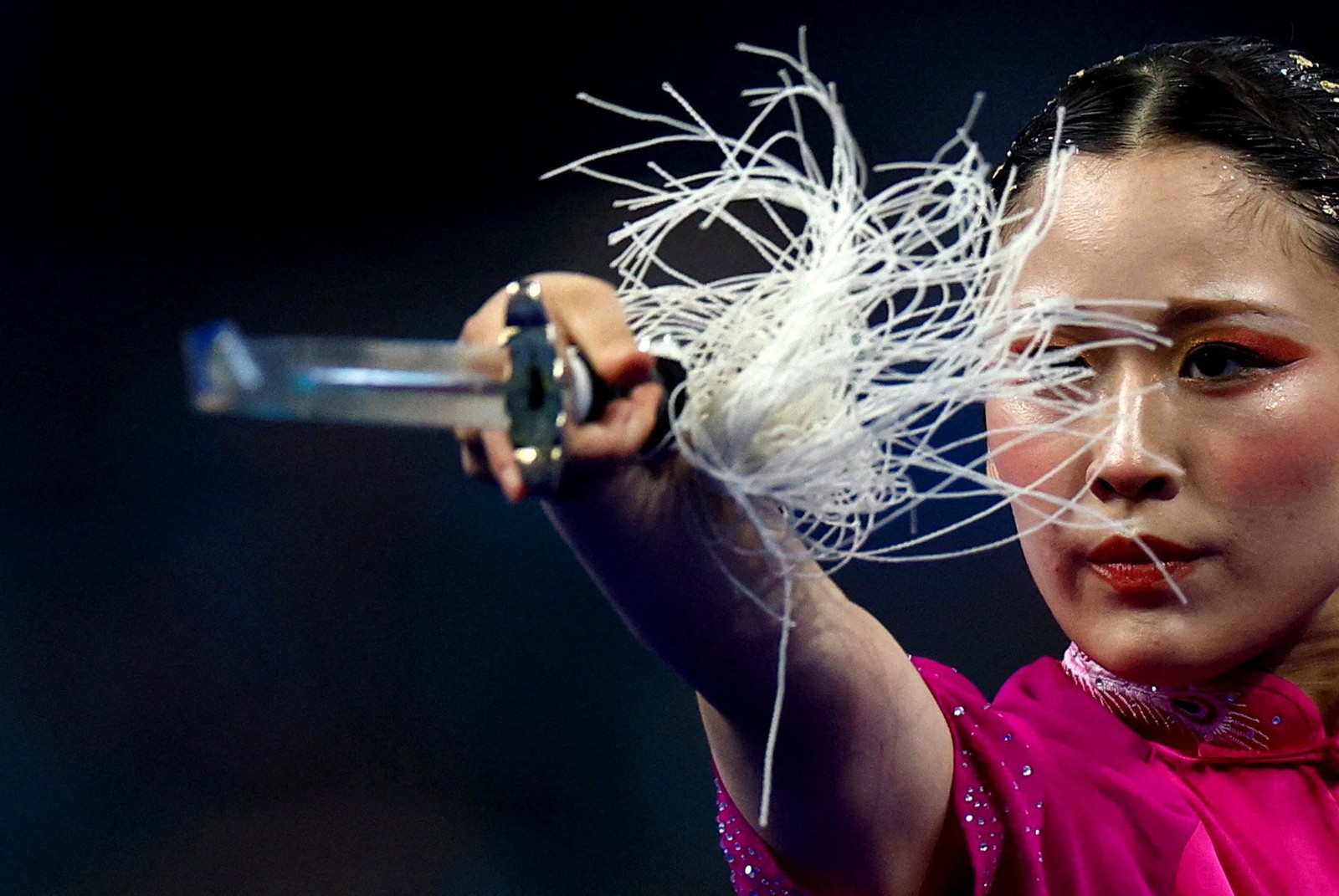 A person weilds a sword with a long tassel.