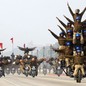 Several stunt teams ride in formations, with multiple people stacked up on single motorcycles.