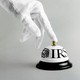 A hand in a white glove rings a bell labeled "IRS"