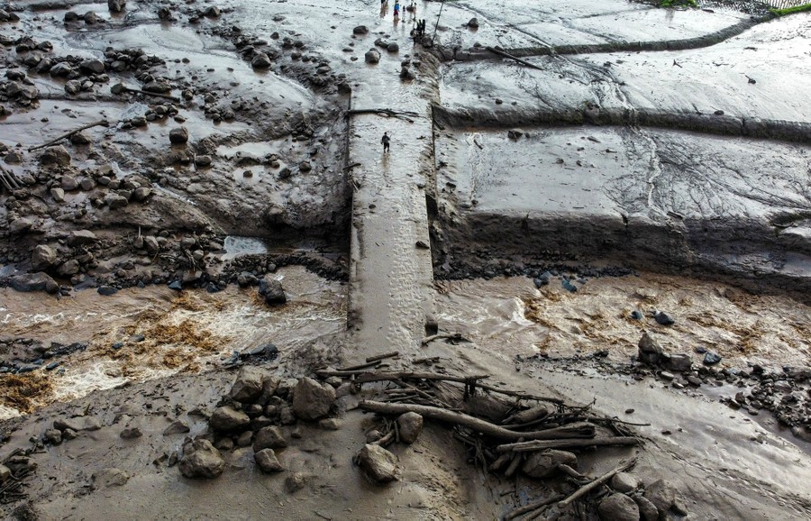 A drone view of a heavily damaged riverbed and bridge