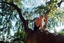 A girl sitting on branch of a large tree