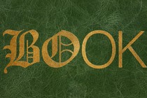The word "book" embossed in foil letters on a green leather background. The first two letters are embellished Gothic fonts and the last two are modern, skinny sans serifs.