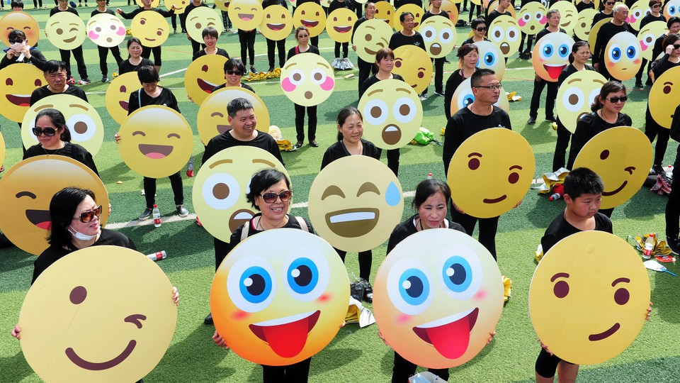 A crowd of people holding up signs with different emoji faces