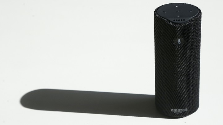 An Amazon Tap sits on a white tabletop.