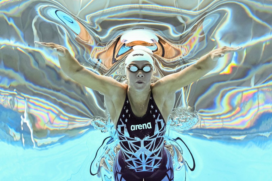 A view of a swimmer in a pool, captured from below, with the water's surface distorting the view above
