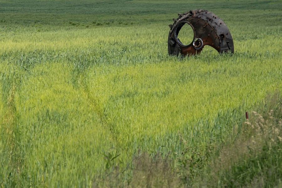 A rusting turret lies on its side in a wheat field.
