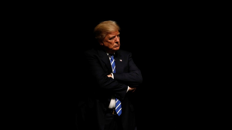 President Trump crossing his arms against a black background