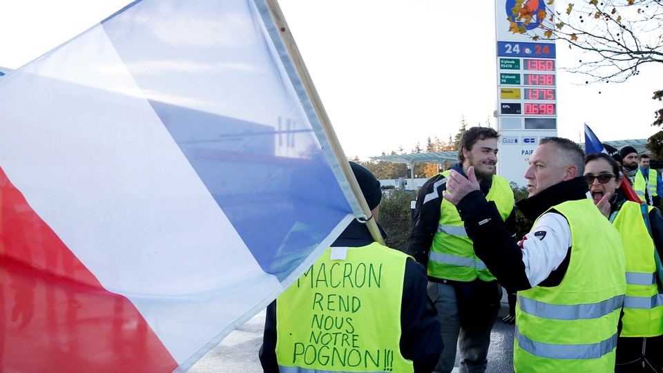 Protesters wearing yellow vests, a symbol of a French drivers' block a gas station to protest against higher fuel prices, in Nantes, France, November 24, 2018. Inscription on the vest reads: "Macron, give us back our money."