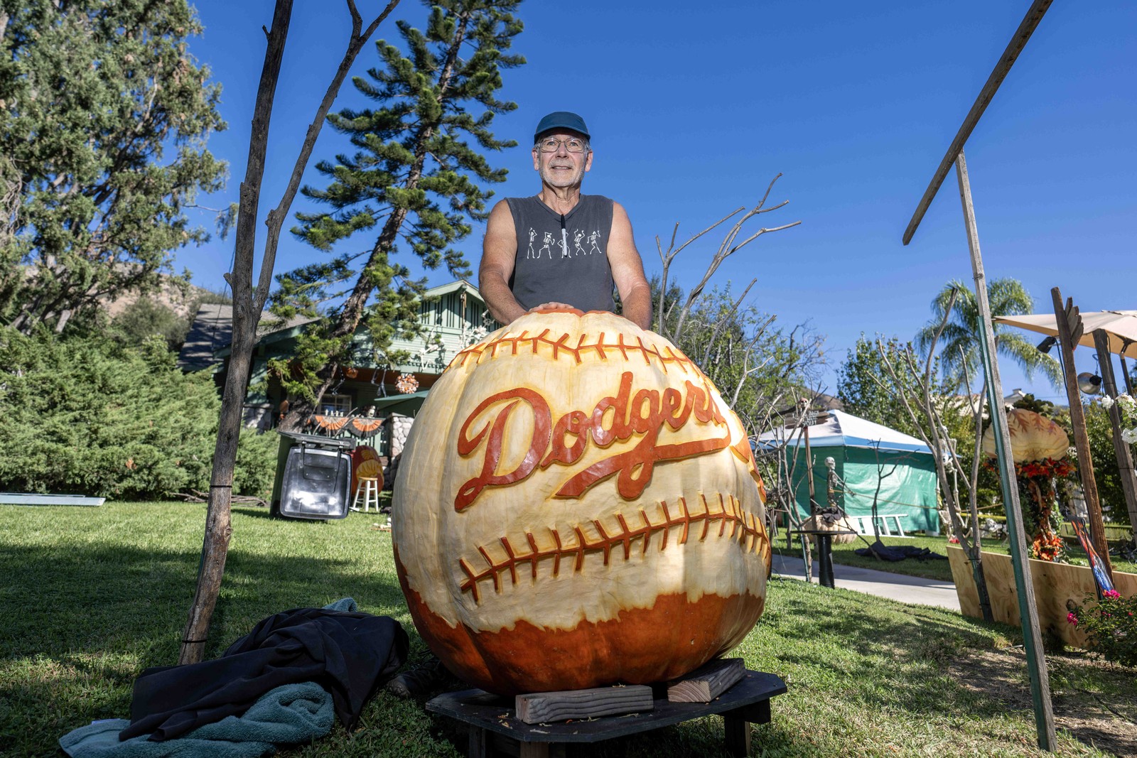 A man stands beside a large pumpkin carved to look like a baseball with 