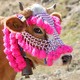 A cow wears colorful tassels and beads on its head.
