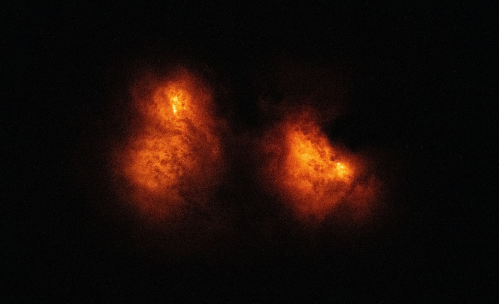 Wildfires seen from orbit at night, through smoke, appearing as orange blotches.