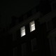 Two lit windows in a home, as seen from across the street