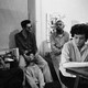 A black and white photo of writers sitting around at a party smoking and drinking